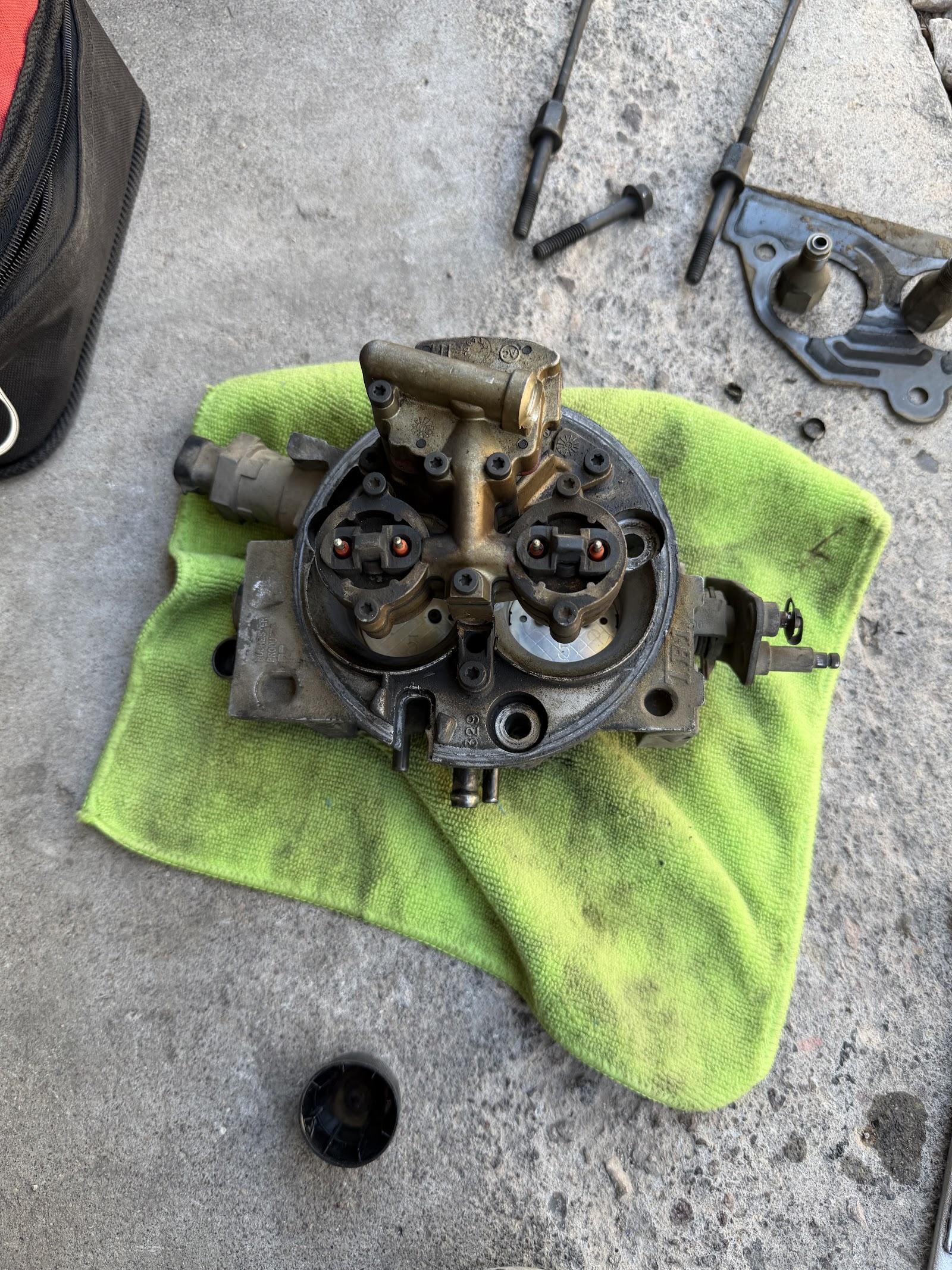 Throttle body injector unit resting on a green towel with tools on concrete